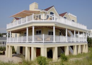 Large beach house sports striped retractable awning on upper balcony 