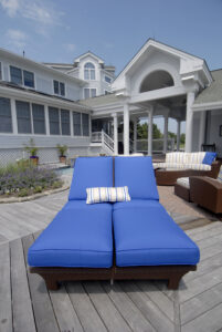 Blue patio lounge chair with white striped pillow outside on deck 