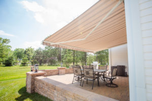 A tan retractable awning over a patio with patio furniture