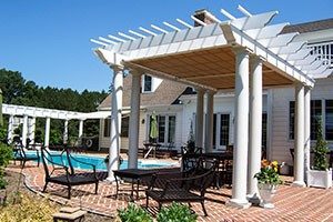 White pergola shades a poolside patio area