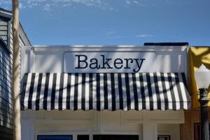 Black and white striped commercial awning protecting storefront of bakery 