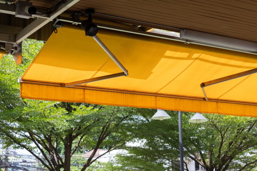Yellow retractable awning with trees in background