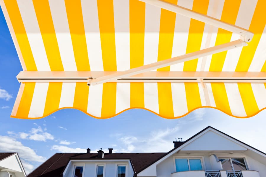 Yellow and white striped awning near house